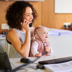 Mère tenant un téléphone de travail tout en tenant un bébé sur ses genoux.