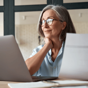 Travailleuse âgée assise à son bureau devant un ordinateur