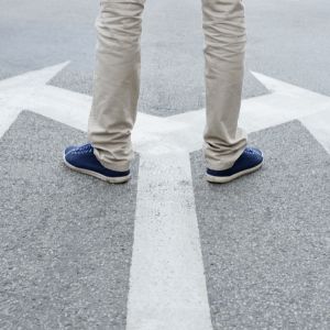 Jambes posées sur la route au dessus d'une flèche indiquant des directions différentes