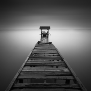 wooden bridge leading out into the water. It is broken in half mid-way.
