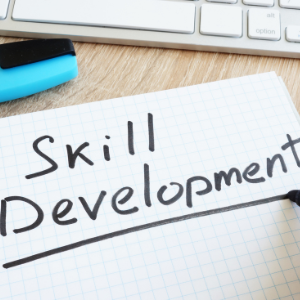 Computer desk with note pad. On note pad written Skill Developement