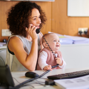 Mother holding work phone while holding baby in lap.